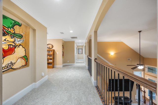 hallway with visible vents, carpet floors, baseboards, and ornamental molding