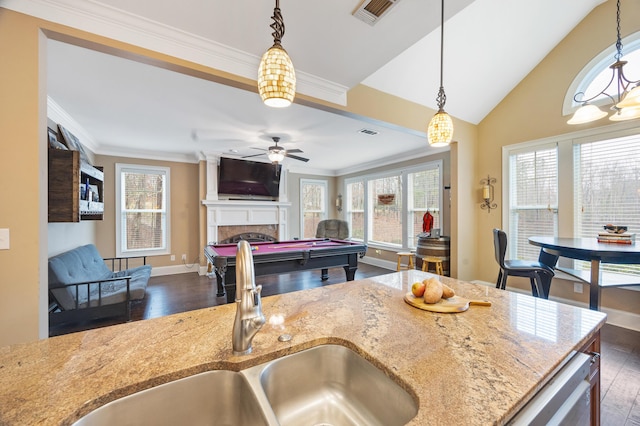 kitchen featuring visible vents, light stone counters, a fireplace, dark wood-style floors, and a sink