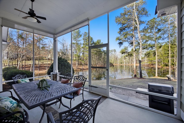 sunroom featuring a water view and a ceiling fan