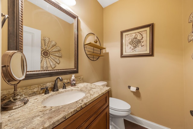 half bathroom with toilet, vanity, and baseboards