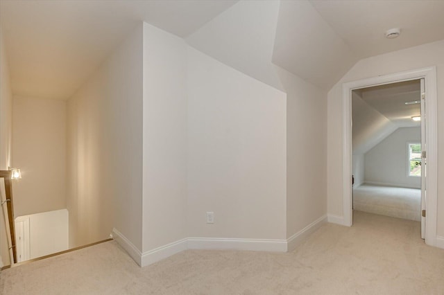 additional living space featuring light carpet, radiator, and vaulted ceiling