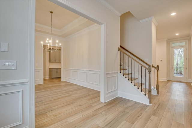 entrance foyer with light wood-type flooring, crown molding, and a notable chandelier