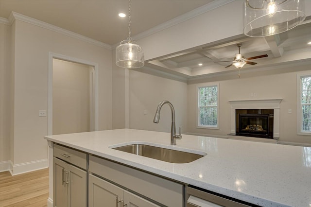 kitchen featuring crown molding, light stone counters, coffered ceiling, and sink