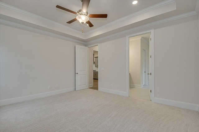 carpeted empty room with a raised ceiling, ceiling fan, and crown molding