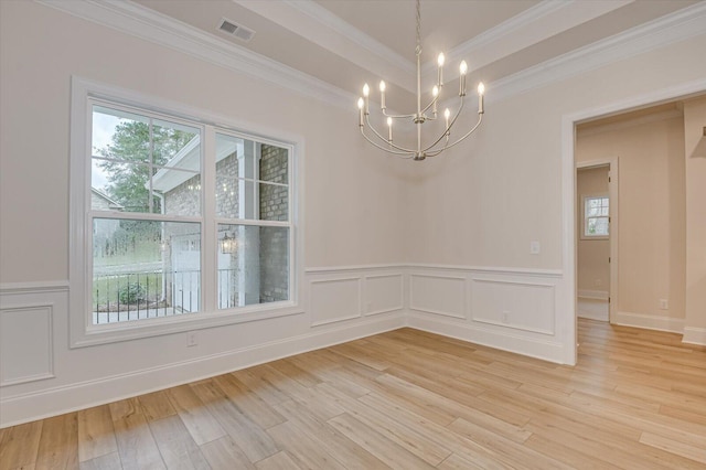 unfurnished dining area featuring a wealth of natural light, crown molding, and a chandelier