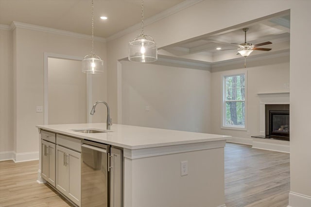 kitchen with white cabinetry, sink, ceiling fan, hanging light fixtures, and an island with sink