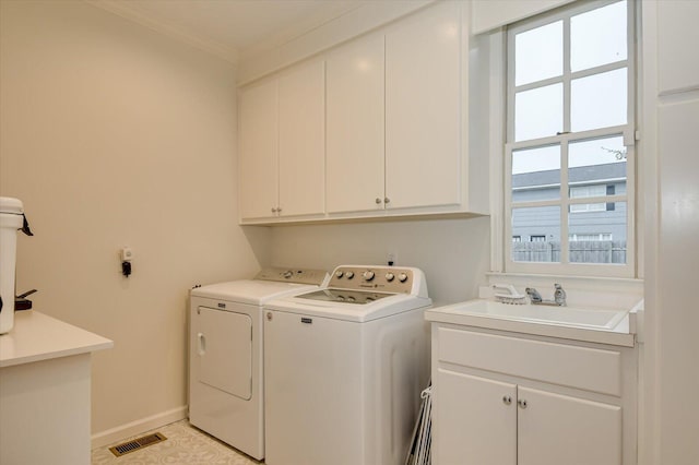 laundry room featuring visible vents, a sink, ornamental molding, cabinet space, and separate washer and dryer