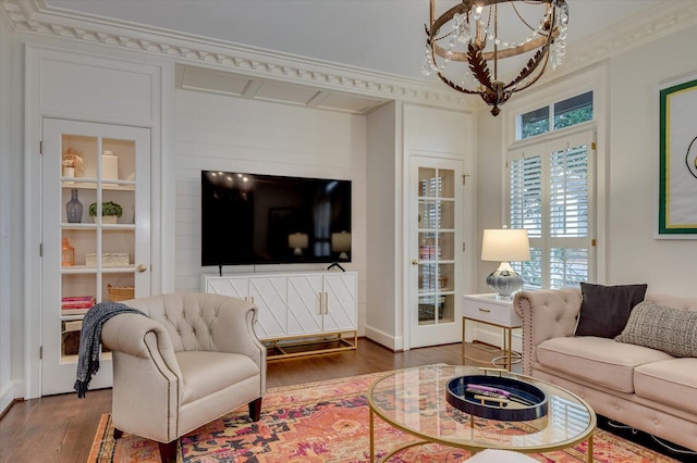 living area featuring an inviting chandelier, wood finished floors, and ornamental molding