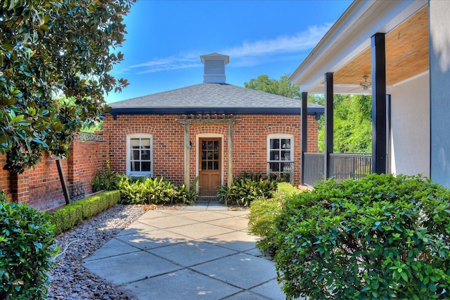 exterior space featuring a patio, a ceiling fan, brick siding, and a shingled roof