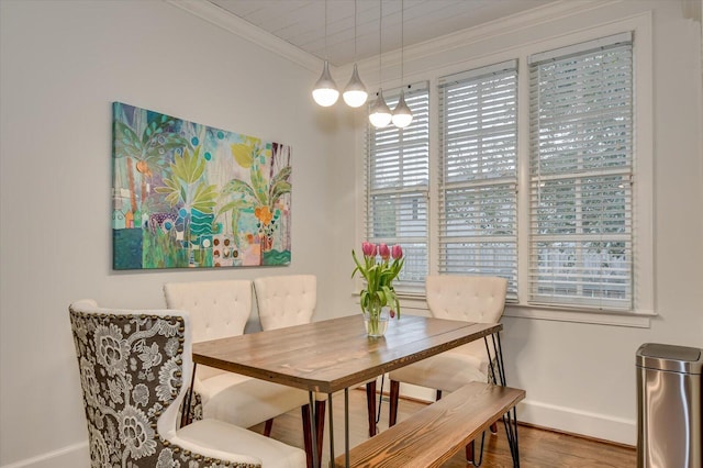 dining room featuring crown molding, baseboards, and wood finished floors