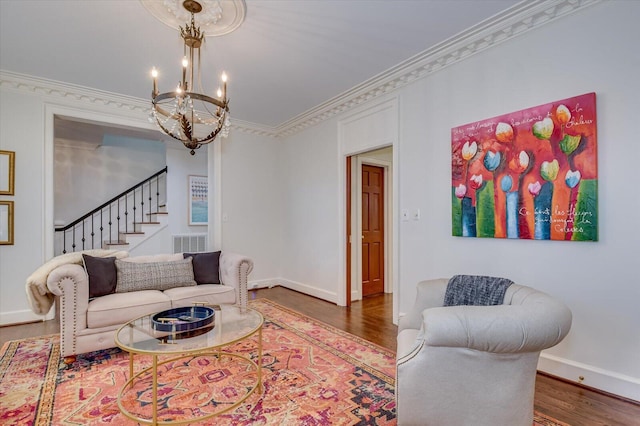 living area featuring baseboards, stairway, ornamental molding, wood finished floors, and a notable chandelier