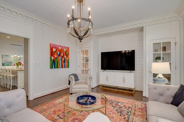 living area featuring baseboards, a notable chandelier, wood finished floors, and ornamental molding