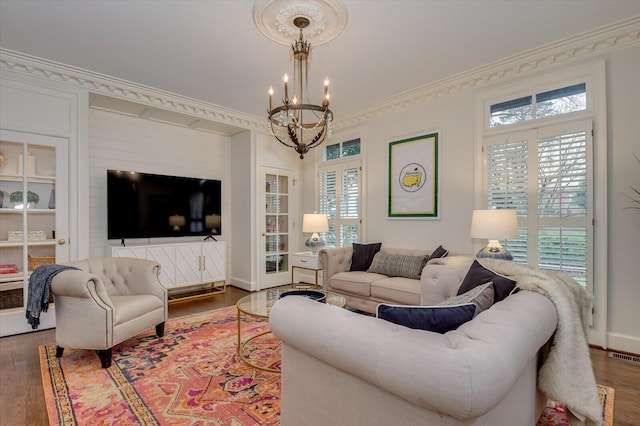 living room featuring an inviting chandelier, crown molding, wood finished floors, and visible vents