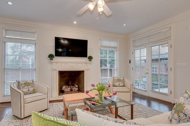 living room featuring crown molding, wood finished floors, and a fireplace with raised hearth