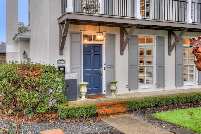 entrance to property featuring stucco siding and a balcony