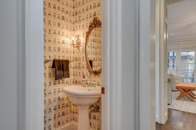 bathroom featuring wood finished floors and wallpapered walls