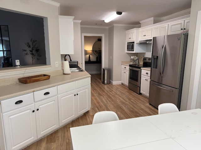 1229 Creek Bend Dr, Grovetown, GA 30813 - kitchen featuring appliances with stainless steel finishes, under cabinet range hood, ornamental molding, white cabinets, and light wood-type flooring