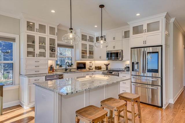 kitchen with a kitchen island, white cabinetry, hanging light fixtures, and appliances with stainless steel finishes