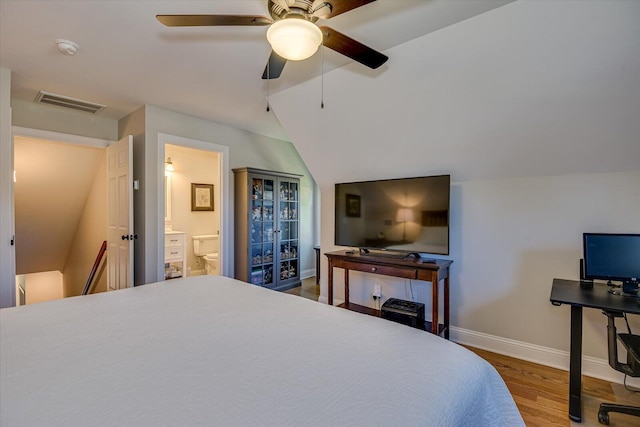 bedroom with hardwood / wood-style floors, vaulted ceiling, ensuite bath, and ceiling fan