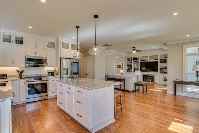 kitchen featuring white cabinets, hanging light fixtures, ceiling fan, appliances with stainless steel finishes, and a kitchen island