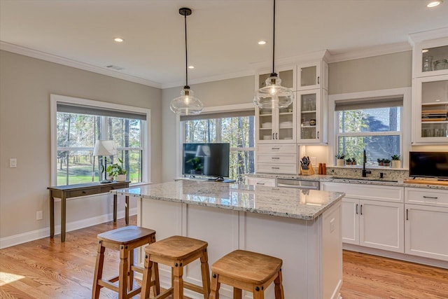 kitchen featuring sink, a center island, stainless steel dishwasher, light hardwood / wood-style floors, and white cabinets