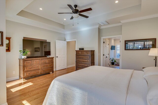 bedroom with a tray ceiling, light hardwood / wood-style flooring, ceiling fan, and ornamental molding