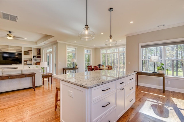 kitchen featuring decorative light fixtures, light hardwood / wood-style floors, a kitchen breakfast bar, and white cabinetry