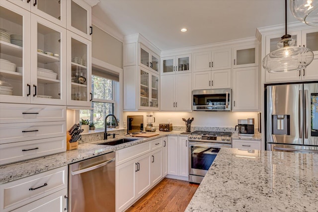 kitchen featuring sink, white cabinets, stainless steel appliances, and decorative light fixtures