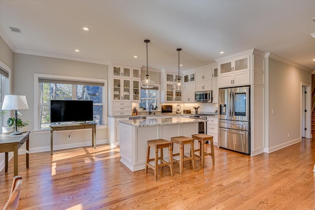 kitchen featuring stainless steel appliances, a kitchen island, pendant lighting, white cabinets, and ornamental molding