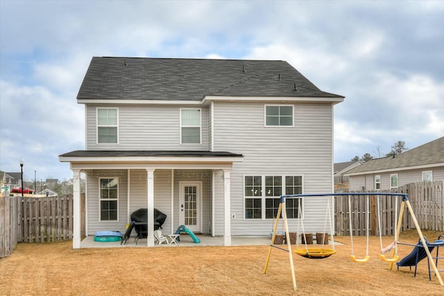 rear view of property with a playground and a patio area