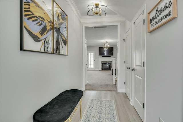 hall featuring crown molding, an inviting chandelier, and light hardwood / wood-style flooring