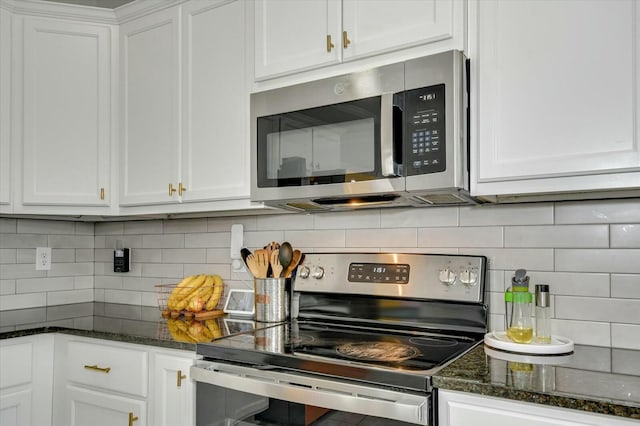 kitchen with dark stone countertops, decorative backsplash, stainless steel appliances, and white cabinets