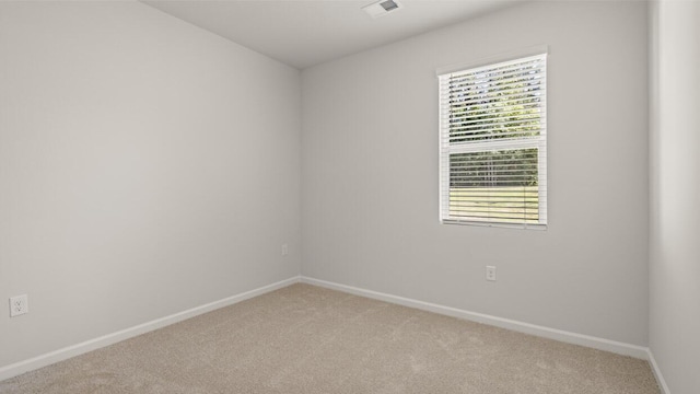 spare room featuring baseboards, visible vents, and light colored carpet
