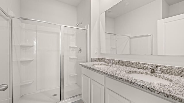 full bathroom with a shower stall, double vanity, and a sink