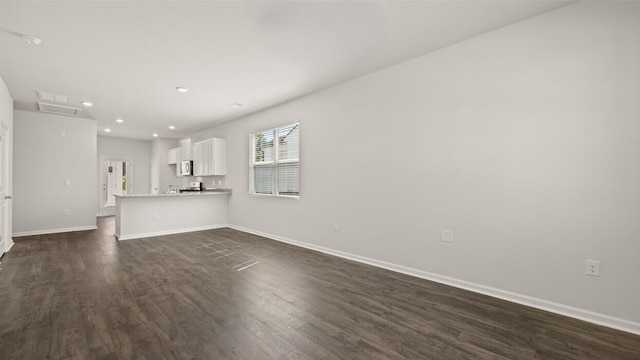 unfurnished living room featuring baseboards, dark wood-style flooring, and recessed lighting