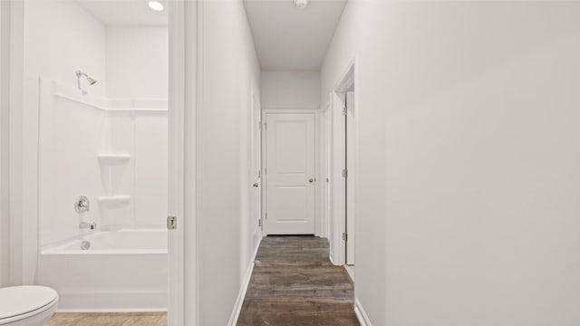 corridor featuring dark wood-type flooring and baseboards