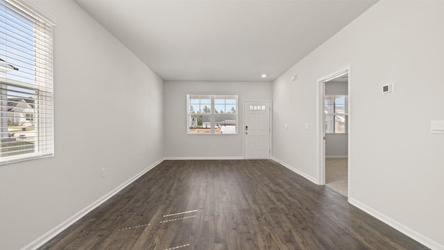 unfurnished room featuring a wealth of natural light, baseboards, and dark wood-style floors