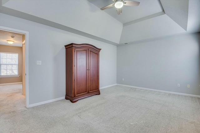 unfurnished bedroom with light colored carpet, ceiling fan, and a tray ceiling