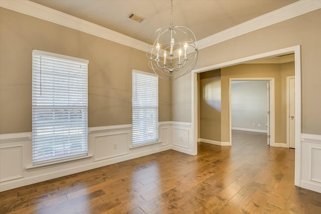 empty room featuring crown molding, a notable chandelier, and hardwood / wood-style flooring