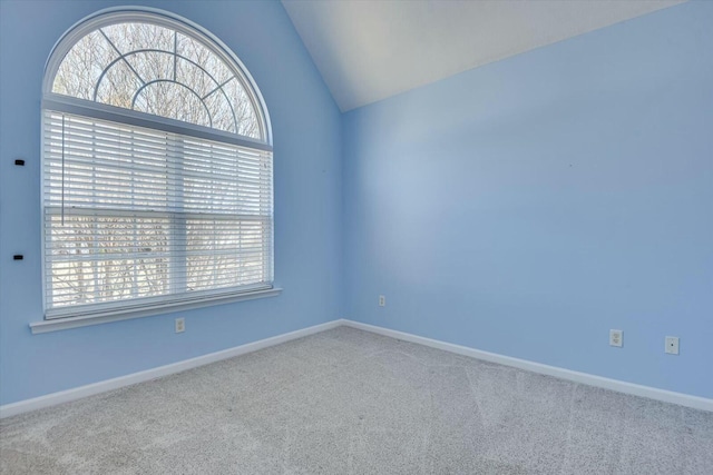 carpeted empty room featuring vaulted ceiling