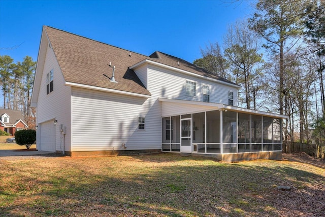 rear view of house featuring a garage, a yard, and a sunroom