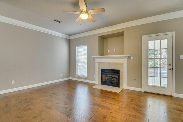 unfurnished living room featuring hardwood / wood-style floors, crown molding, a tile fireplace, and ceiling fan