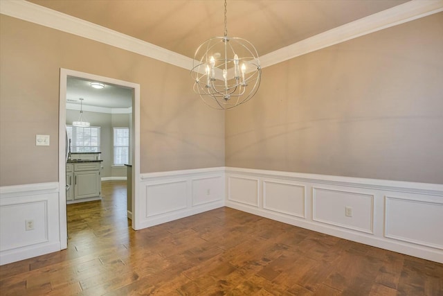 unfurnished dining area featuring ornamental molding, hardwood / wood-style floors, and a notable chandelier