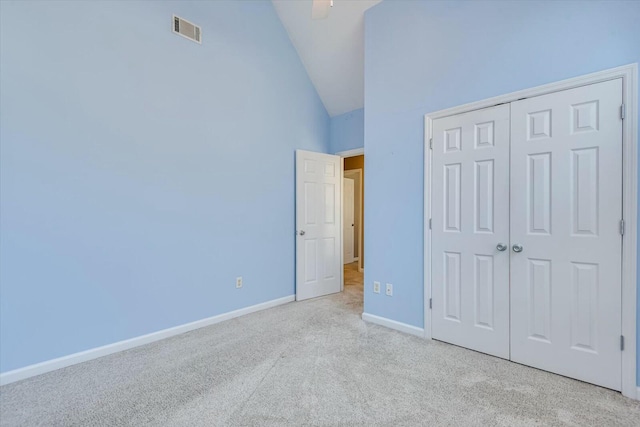 unfurnished bedroom featuring light colored carpet, high vaulted ceiling, and a closet