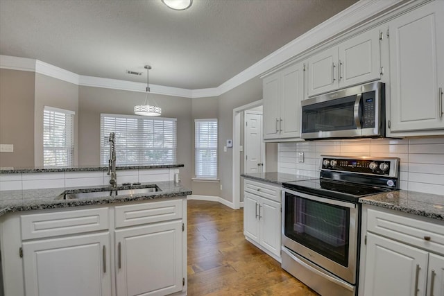 kitchen featuring sink, ornamental molding, stainless steel appliances, and white cabinets