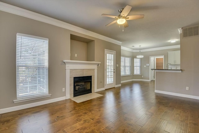 unfurnished living room with crown molding, ceiling fan, a fireplace, and dark hardwood / wood-style flooring