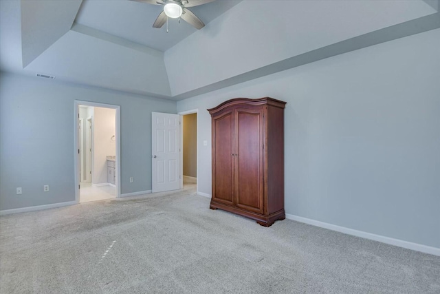 unfurnished bedroom with ceiling fan, light colored carpet, a raised ceiling, and ensuite bath