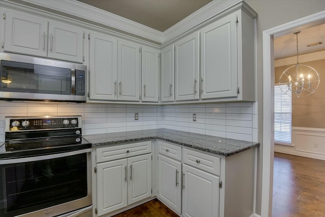 kitchen with crown molding, dark wood-type flooring, appliances with stainless steel finishes, white cabinetry, and dark stone countertops