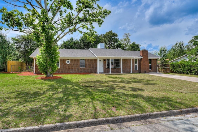 ranch-style house featuring driveway, brick siding, a chimney, fence, and a front yard