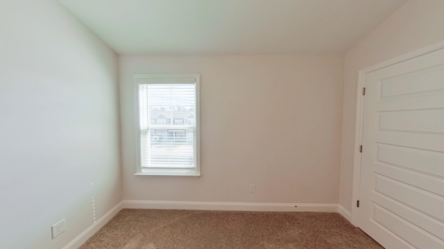 carpeted empty room featuring baseboards